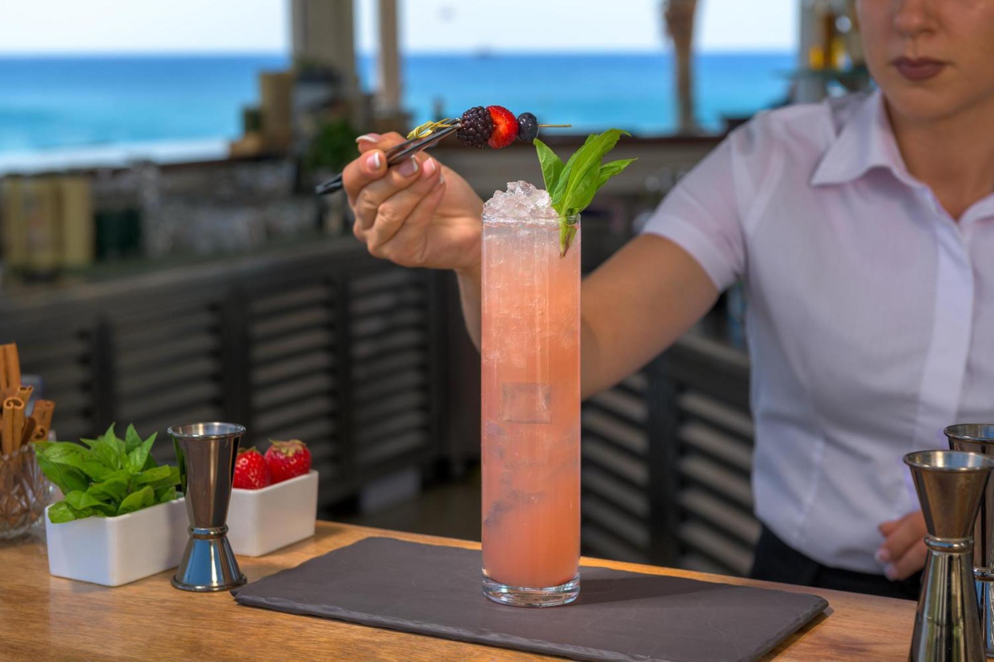 Rodos Palladium Leisure&Wellness Kallithéa Exterior foto A bartender garnishes a cocktail with a fruit skewer.